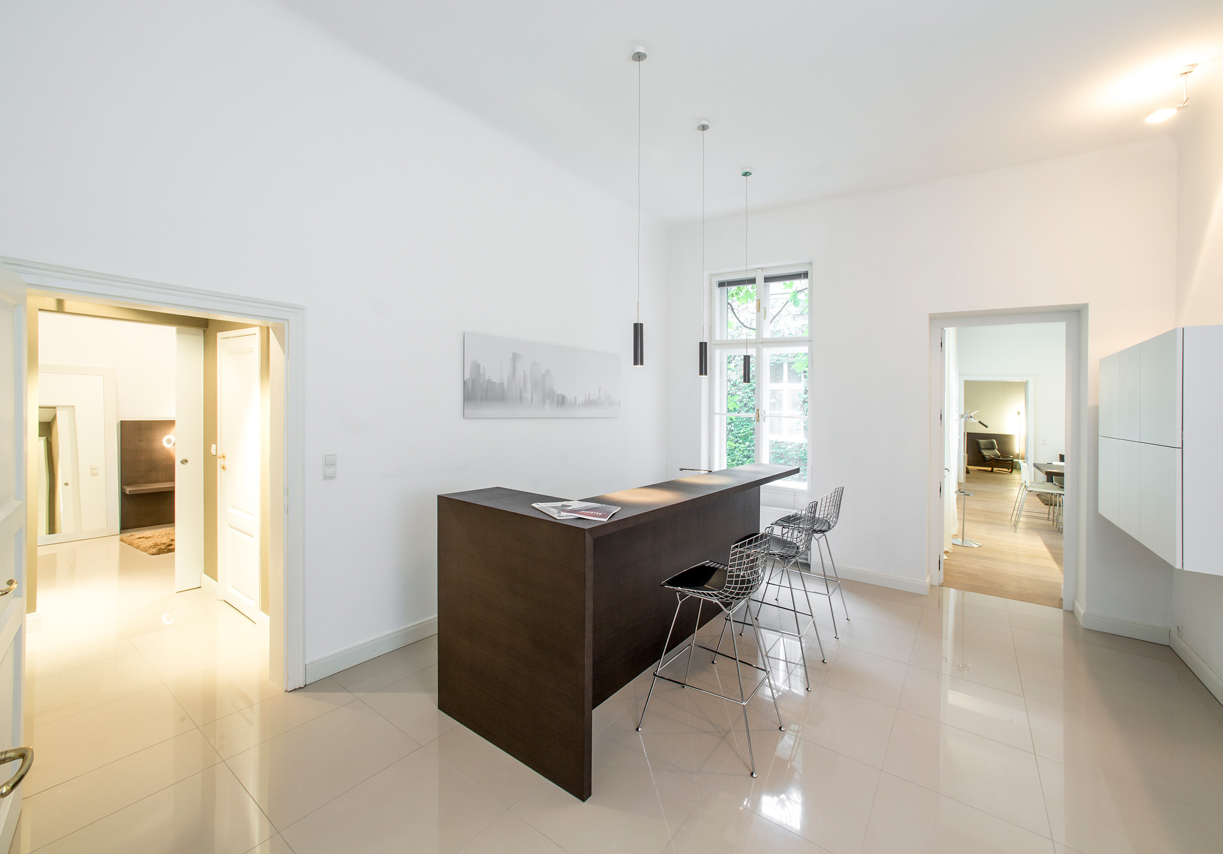 Bright apartment with high ceilings, a dark wood breakfast bar and views through to adjoining rooms