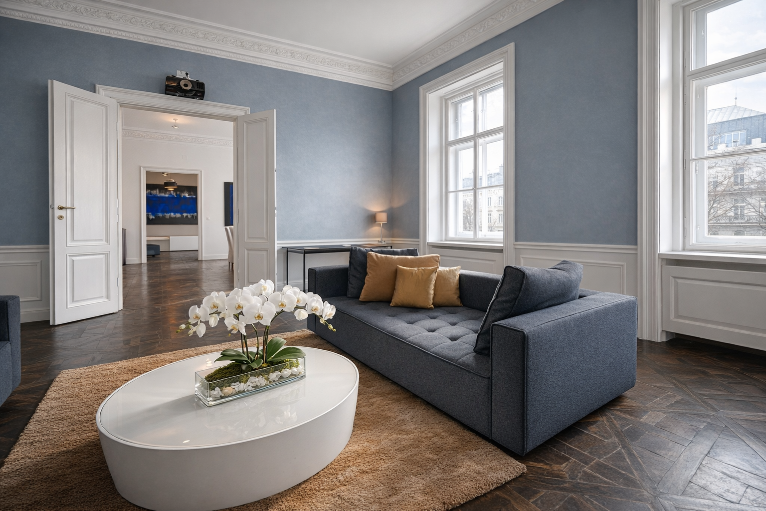 Blue-grey salon with tufted sofa, gold cushions, parquet floor and tall windows onto the Ringstrasse